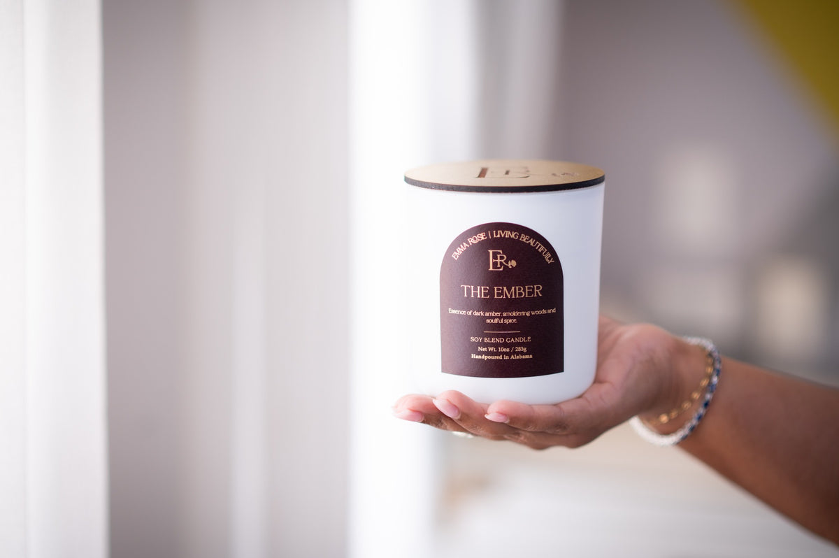 The Ember palo santo and oud candle held in soft natural light